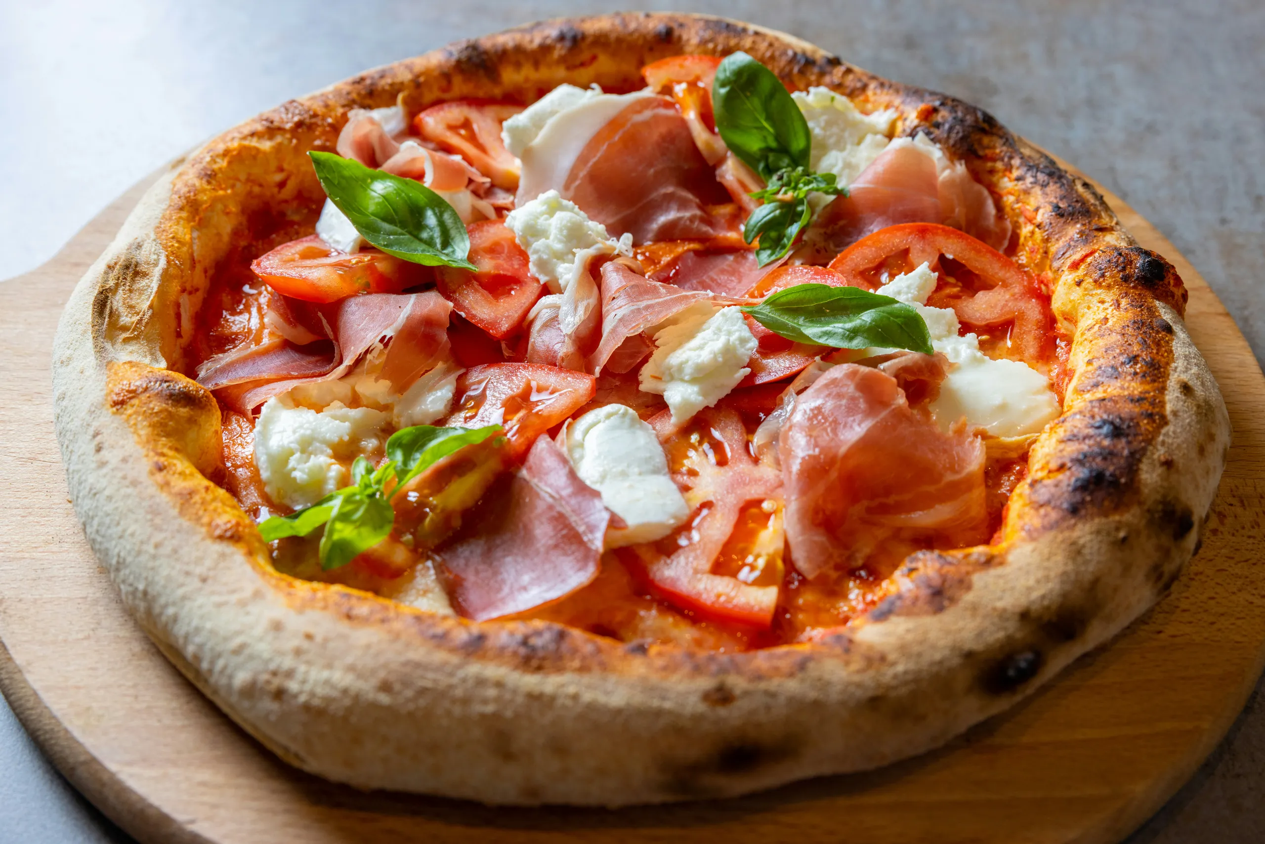 Pizza con prosciutto, tomate y mozzarella